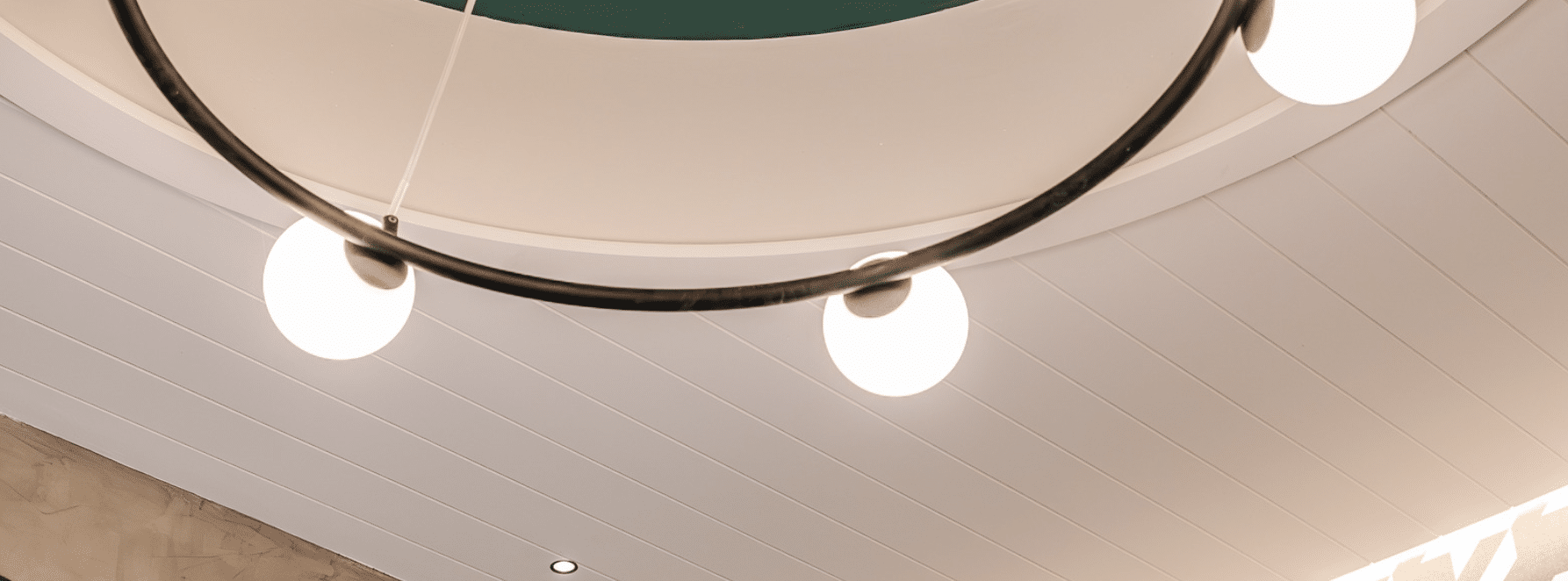 Ceiling view with circular light fixtures against white panels.